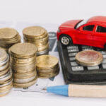 pile-de-pieces-de-monnaie-calculatrice-voiture-jouet-et-stylo-sur-le-gabarit