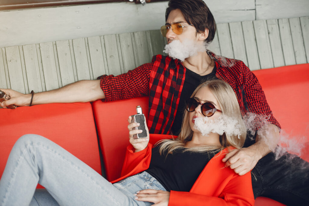 Stylish young couple with vape in a city
