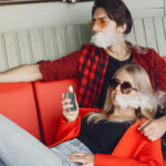 Stylish young couple with vape in a city