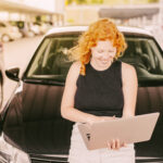 woman-with-laptop-sitting-hood-car