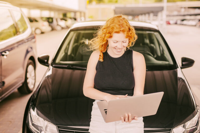 woman-with-laptop-sitting-hood-car
