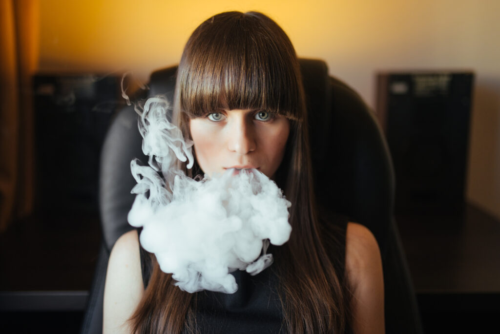 Young beautiful girl exhaling smoke from a hookah and looking at the camera